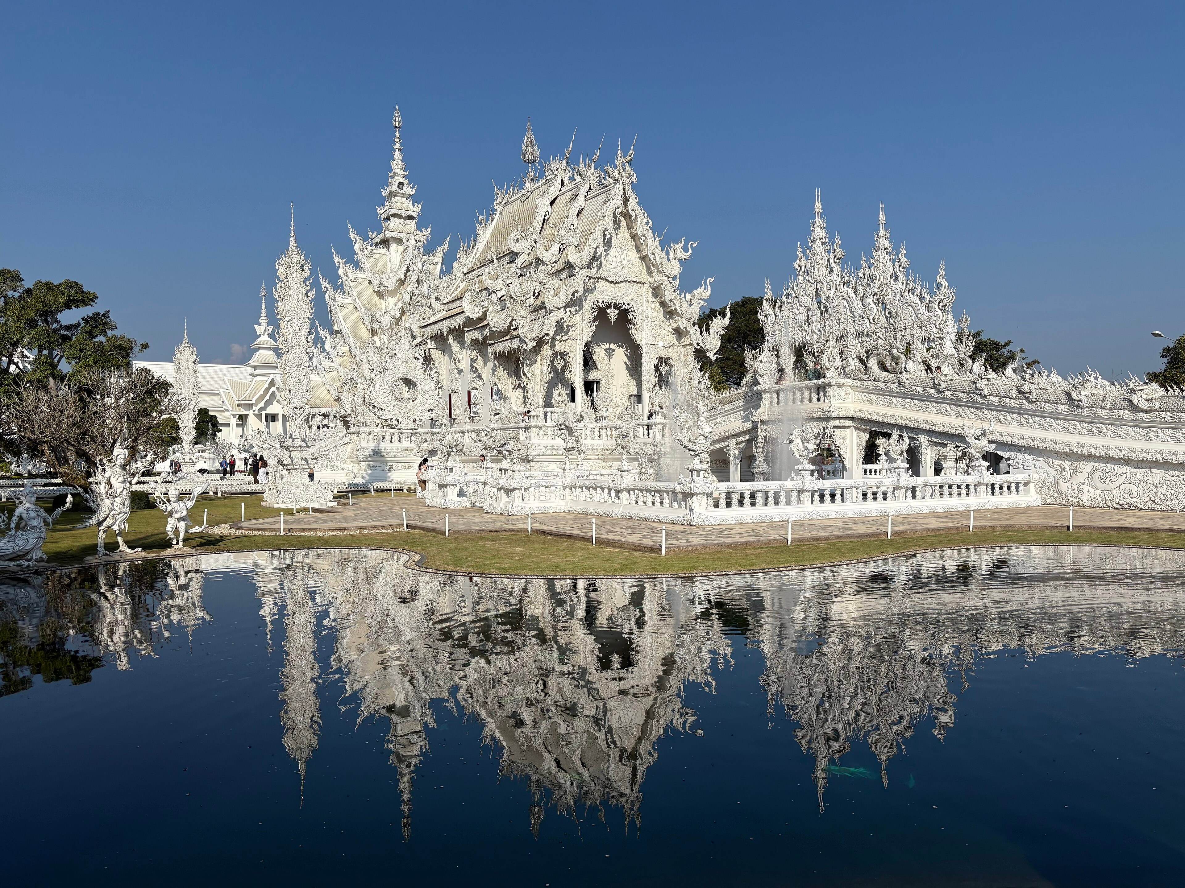 The white ubosot of Wat Rong Khun reflected in the pond in front of it